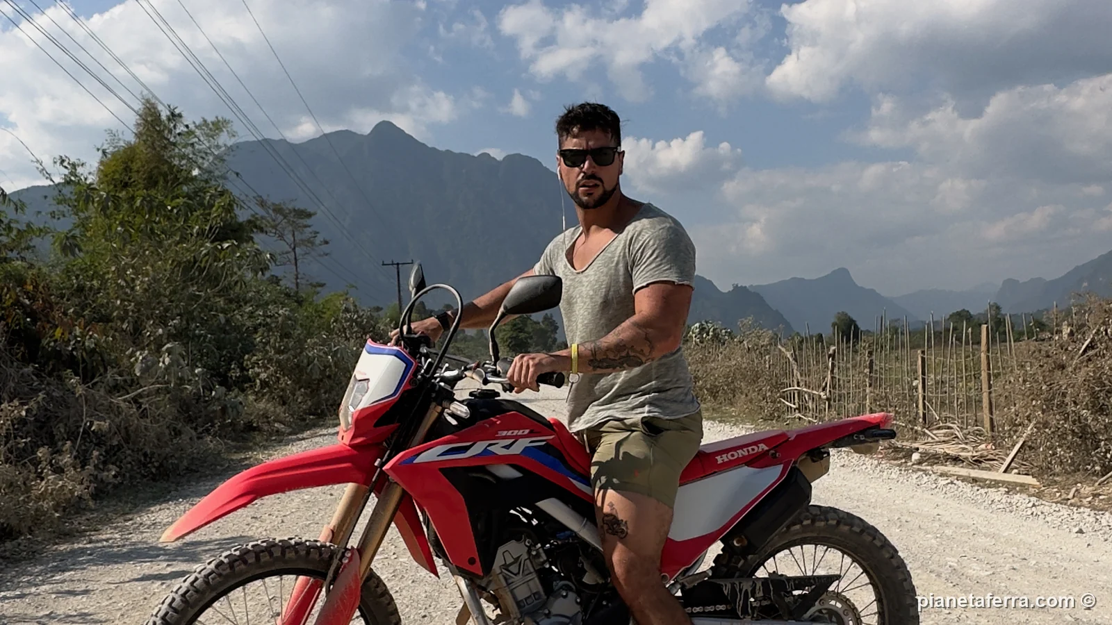 Luca su una moto da cross su una strada sterrata intorno a Vang Vieng, con le montagne carsiche dietro
