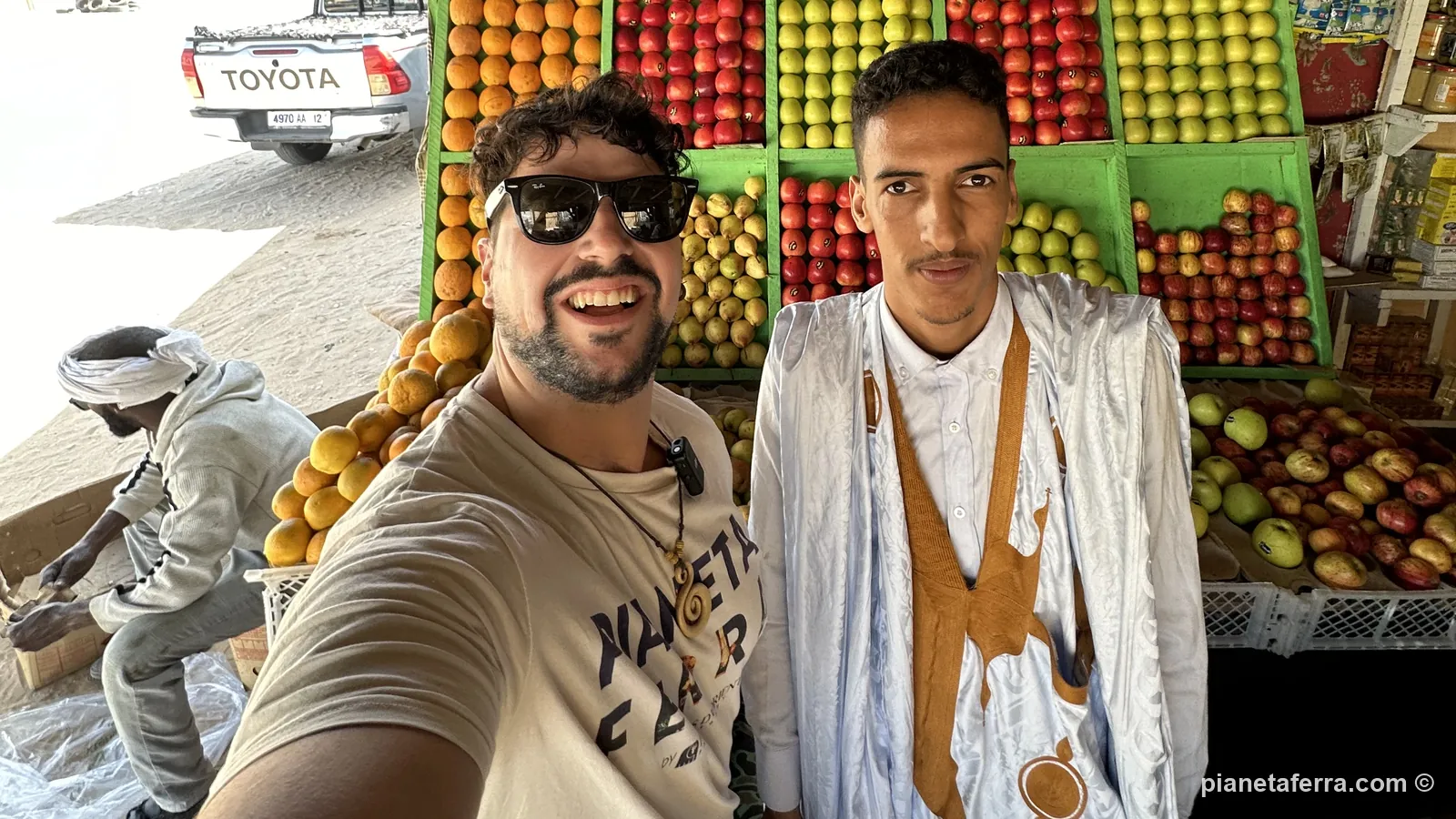 Luca con Bouh, la guida del viaggio in Mauritania, davanti a un banco di frutta