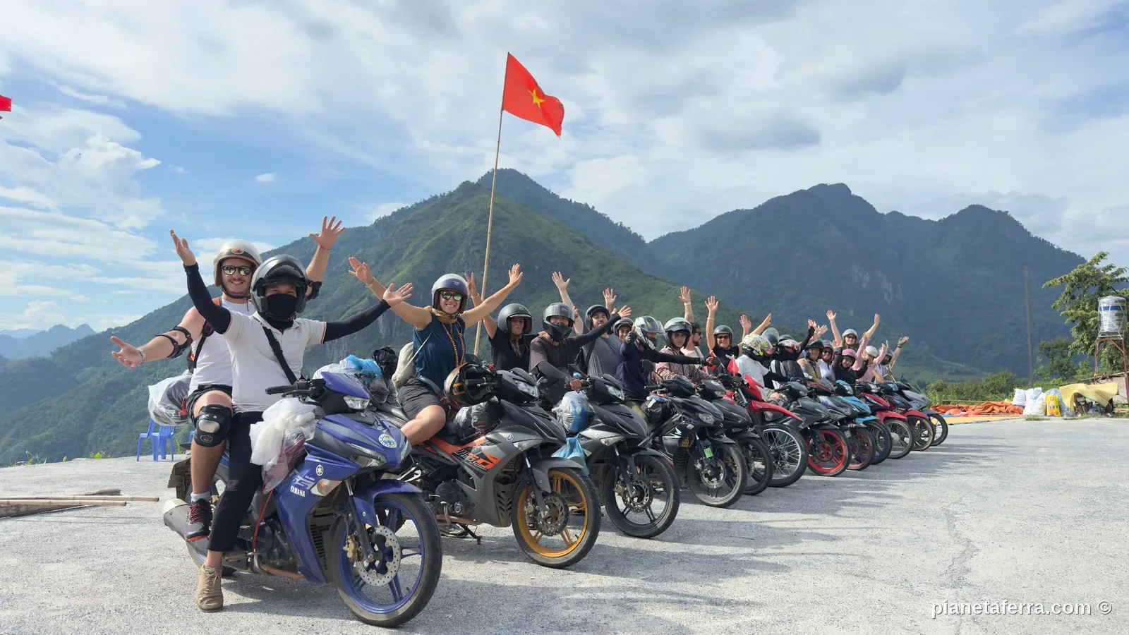 Gruppo di viaggiatori in moto sull'Ha Giang Loop con bandiera del Vietnam