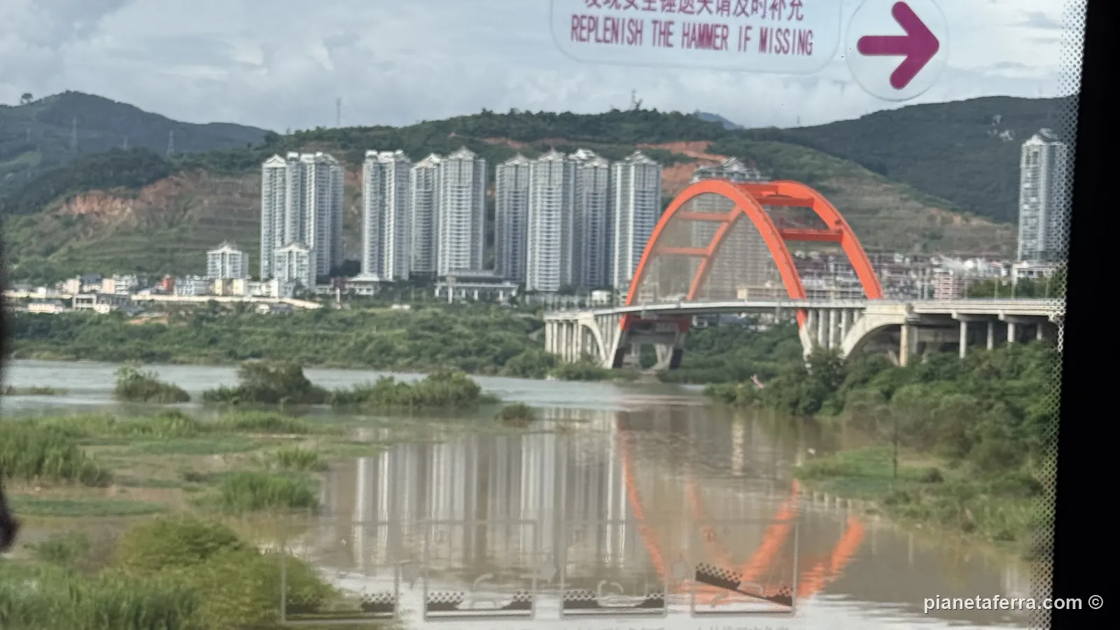 La parte moderna di Jinghong con i palazzi e il ponte rosso sul Mekong, vista dal finestrino del bus