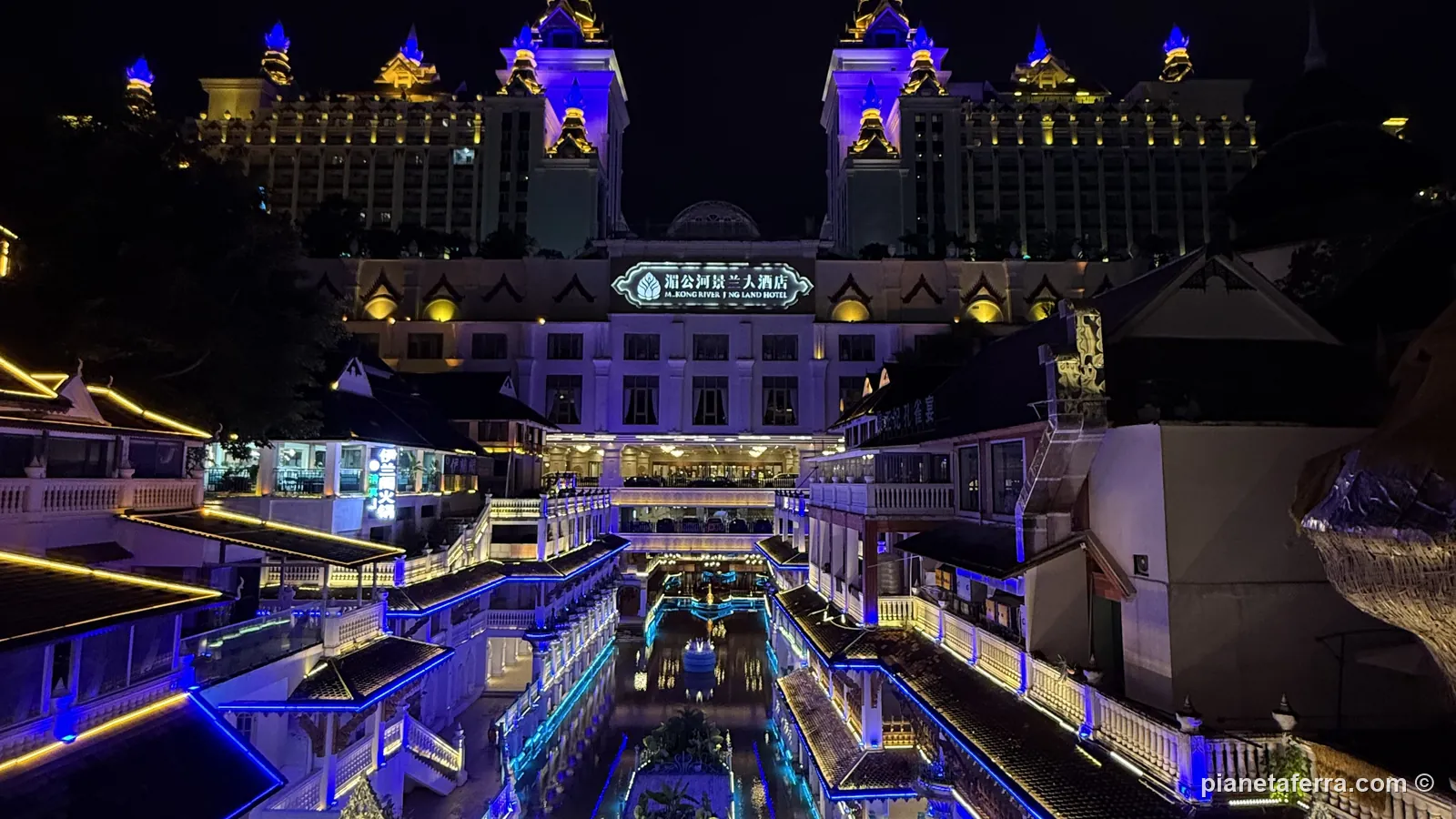 Un complesso illuminato di sera a Jinghong, con i neon viola e blu