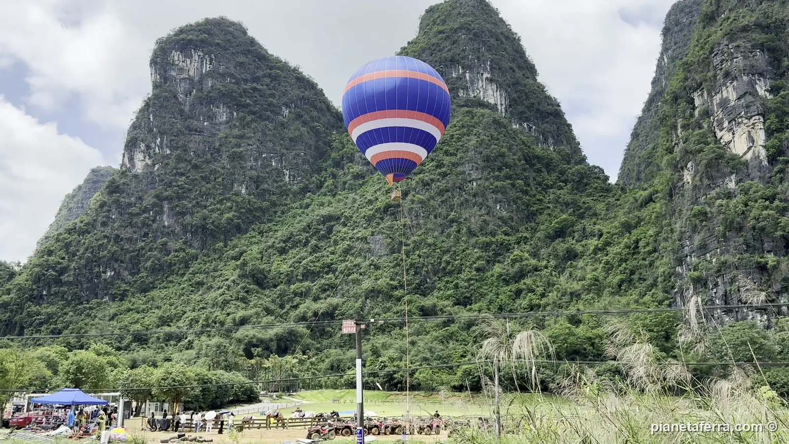 Una mongolfiera tra i picchi carsici nella campagna del fiume Yulong, vicino a Yangshuo, a maggio 2024