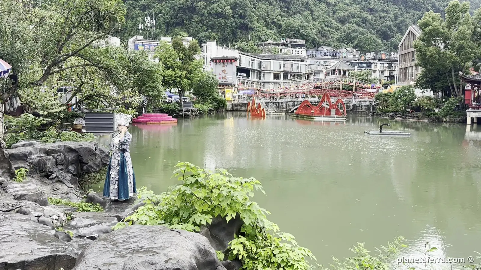 Le barche rosse sul fiume nel centro di Yangshuo, con i picchi carsici dietro il paese, a maggio 2024